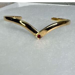 Avon gold tone V shaped cuff bracelet with faux ruby or garnet. Large